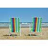 Two colorful beach chairs on the ocean shore