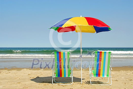 Beach chairs and umbrella on the ocean shore with surf in the background, horisontal Beach chairs and umbrella on the ocean shore with surf in the background, horisontal