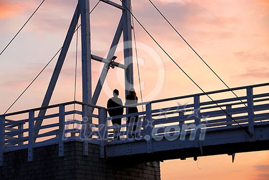 Couple watching sunset on a footbridge in Perkins Cove, Maine Couple watching sunset on a footbridge in Perkins Cove, Maine