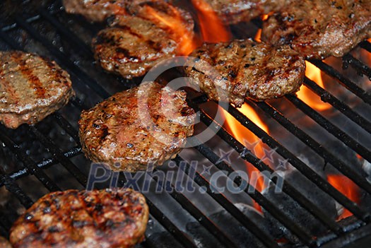 Hamburgers cooking on barbeque grill with flames Hamburgers cooking on barbeque grill with flames
