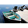 Two wooden adirondack chairs on a boat dock on a beautiful still lake with sky reflection