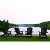 Four wooden adirondack chairs on a shore of a beautiful lake at dusk