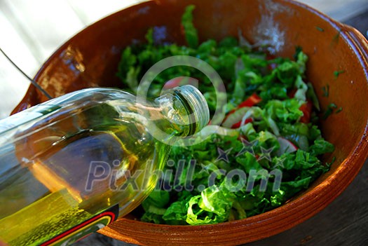 Olive oil being poured into garden salad for salad dressing Olive oil being poured into garden salad for salad dressing