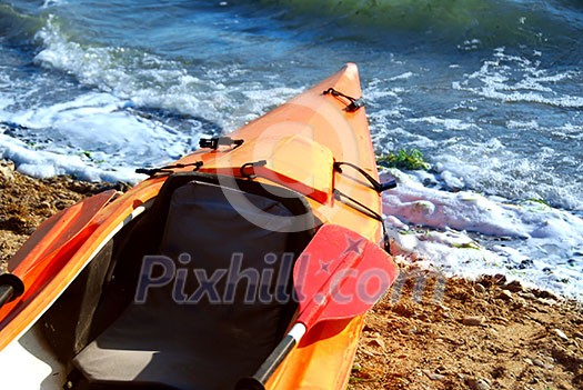 Orange kayak on a sandy shore of a river Orange kayak on a sandy shore of a river
