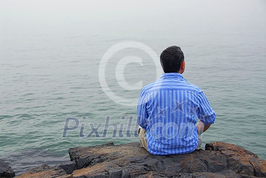 Man looking at the foggy ocean. Uncertain future concept.