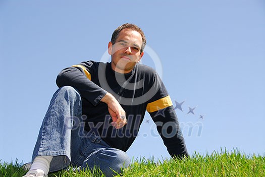 Man sitting on grass, cloudless sky background