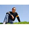 Man sitting on grass, cloudless sky background