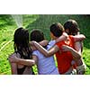 Group of preteen girls having fun outside running through sprinkler