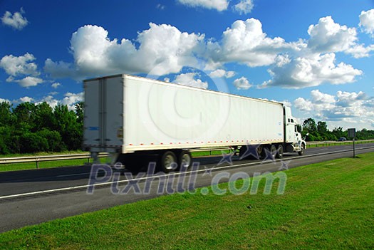 Fast moving truck with white container on highway, blurred because of motion
