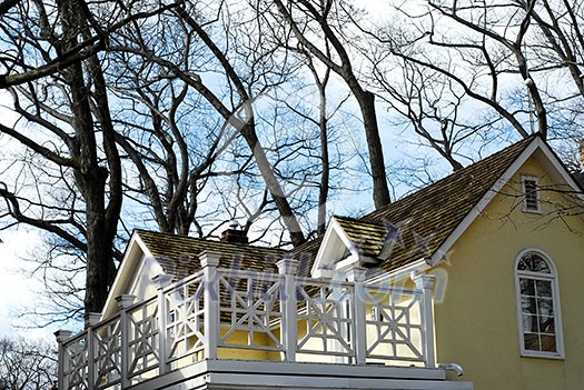 Yellow house with white balcony surrounded by oak trees Yellow house with white balcony surrounded by oak trees