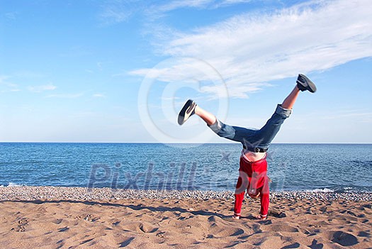 Young girl doing cartwheel on a beach
