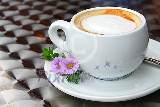 Cup of coffee with flowers on saucer