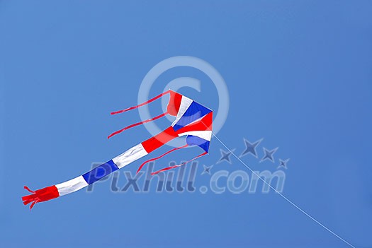 Kite with american flag colors flying in clear blue sky Kite with american flag colors flying in clear blue sky