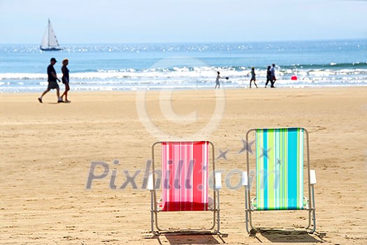 Two empty colorful beach chairs on a sandy beach