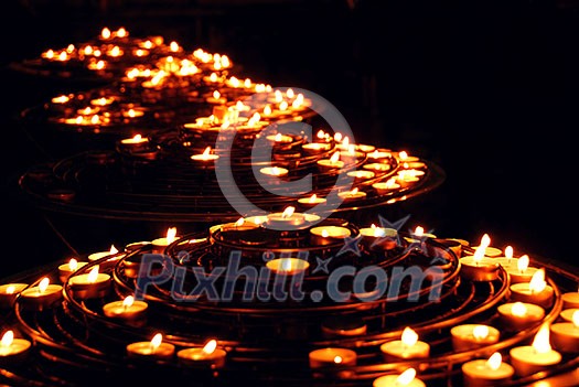 Rows of burning candles in a cathedral