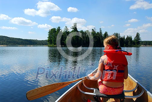 Young girl in canoe paddling on a scenic lake