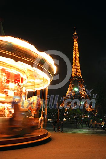 Spinning traditional carousel in Paris France at night with Eiffel tower in the background