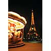 Spinning traditional carousel in Paris France at night with Eiffel tower in the background