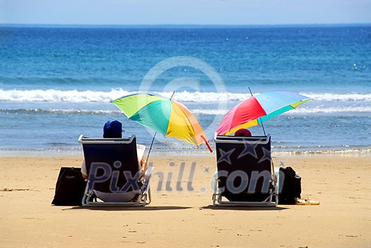 A couple relaxing on a beach under colorful umbrellas