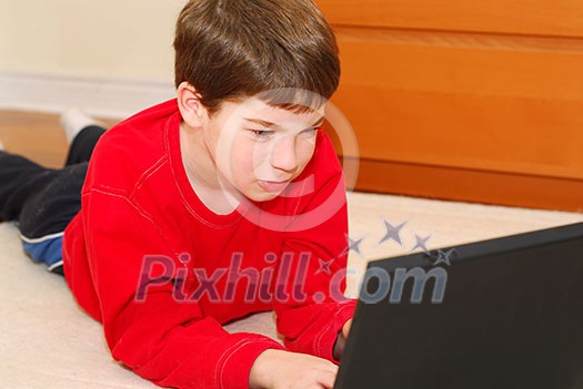 Little boy lying on the floor with portable computer