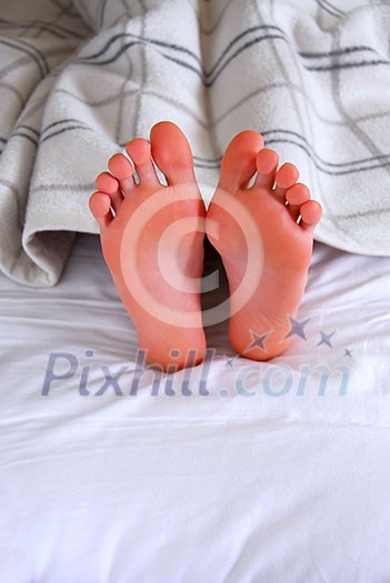 Child's feet sticking out of a blanket in a bed