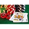 Stacks of gambling chips, playing cards and dice on green background