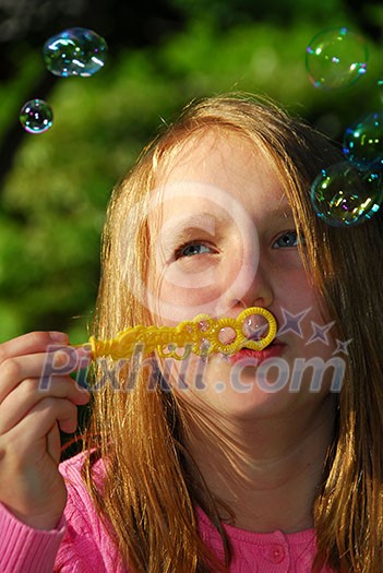 Young girl blowing soap bubbles in a park