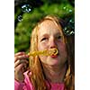 Young girl blowing soap bubbles in a park