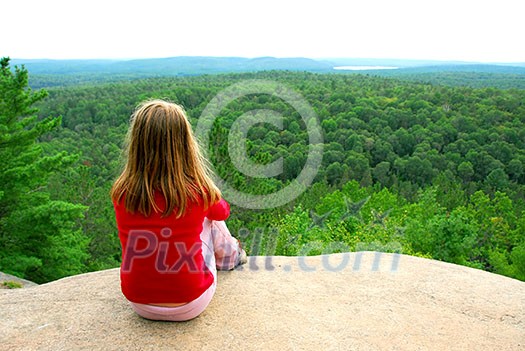 Young girl sitting on an edge of a cliff Young girl sitting on an edge of a cliff