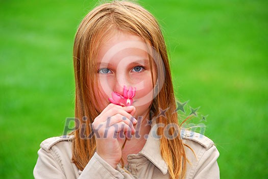 Young girl holding a pink flower in her hand Young girl holding a pink flower in her hand