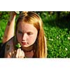 Young girl lying on green grass outside holding a green plant