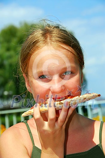Young girl eating a slice of cheese pizza outside