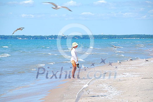 Young girl on a beach among flying seagulls Young girl on a beach among flying seagulls