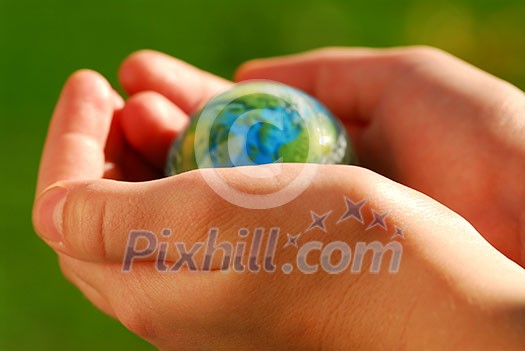 Child's hands holding a globe on green background