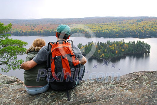 Parent and child sitting on cliff edge enjoying scenic view Parent and child sitting on cliff edge enjoying scenic view