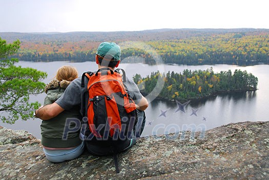 Parent and child sitting on cliff edge enjoying scenic view