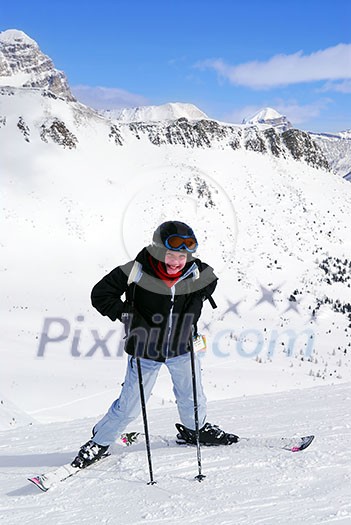 Young girl downhill skiing on the backdrop of scenic view in Canadian Rocky mountains ski resort