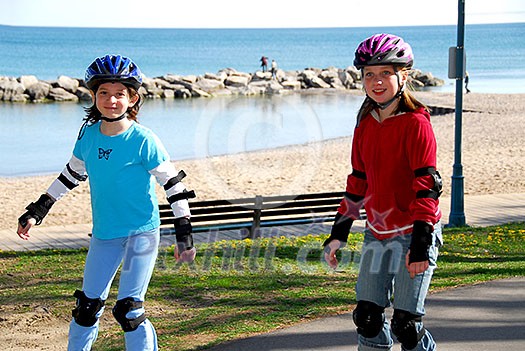 Two girls rollerblading on lake shore trail Two girls rollerblading on lake shore trail