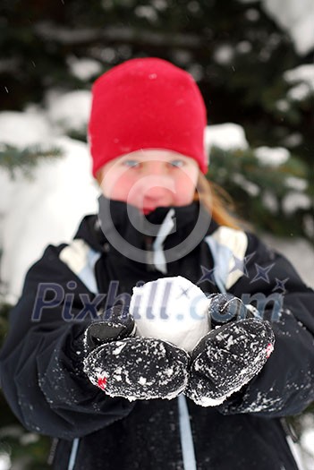 Young girl holding a snowball in her hands