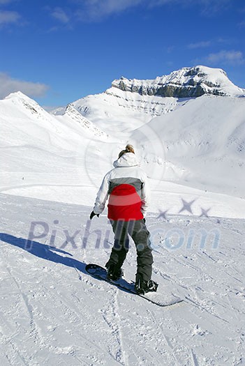 Girl snowboarding on the backdrop of scenic view in Canadian Rocky mountains ski resort