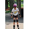 Young girl rollerblading in a summer park