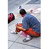 Street artist drawing with chalk on sidewalk