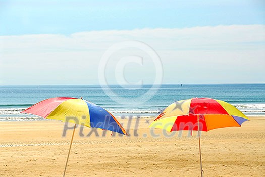 Two beach ubrella standing on ocean shore Two beach ubrella standing on ocean shore