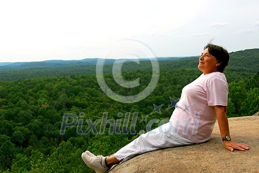 Mature woman sitting on cliff edge enjoying scenery