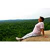 Mature woman sitting on cliff edge enjoying scenery