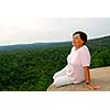 Mature woman sitting on cliff edge enjoying scenery