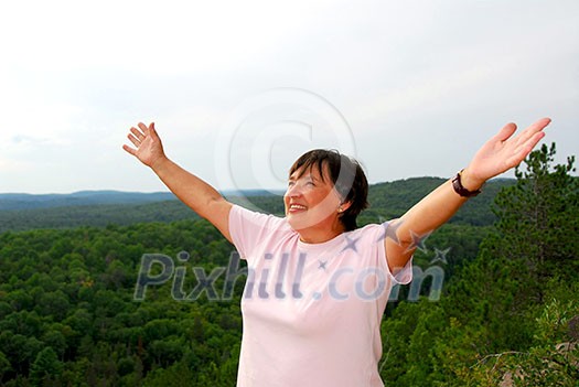 Mature woman on hilltop raising her arms Mature woman on hilltop raising her arms
