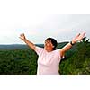Mature woman on hilltop raising her arms