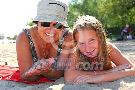 Grandmother and granddaughter relaxing on a sandy beach