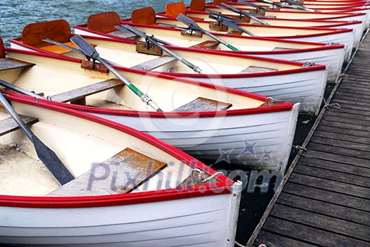 Row of docked wooden rowing boats for rent Row of docked wooden rowing boats for rent